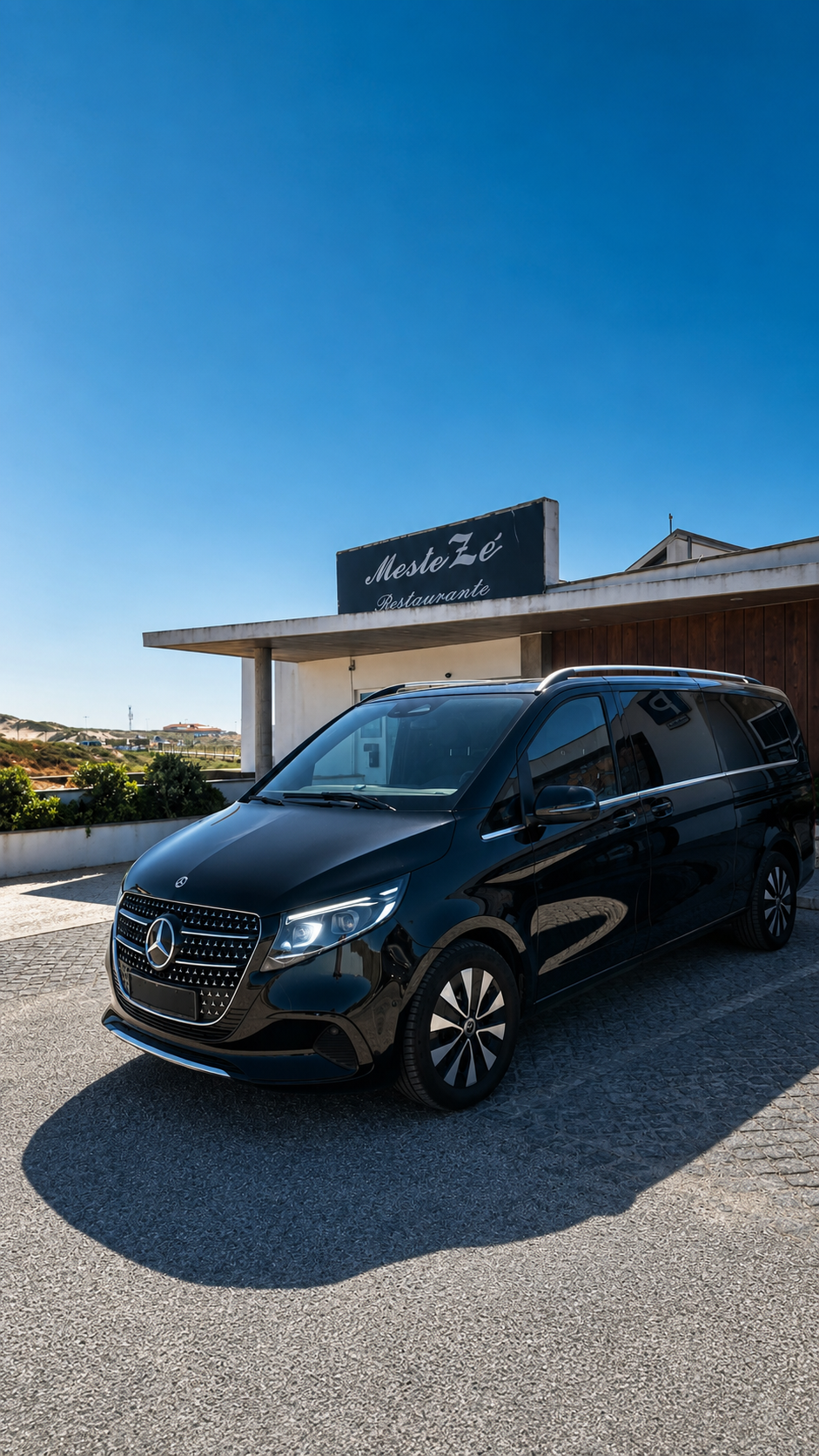 Mercedes Classe V preto em frente ao restaurante Meste Zé sob céu azul